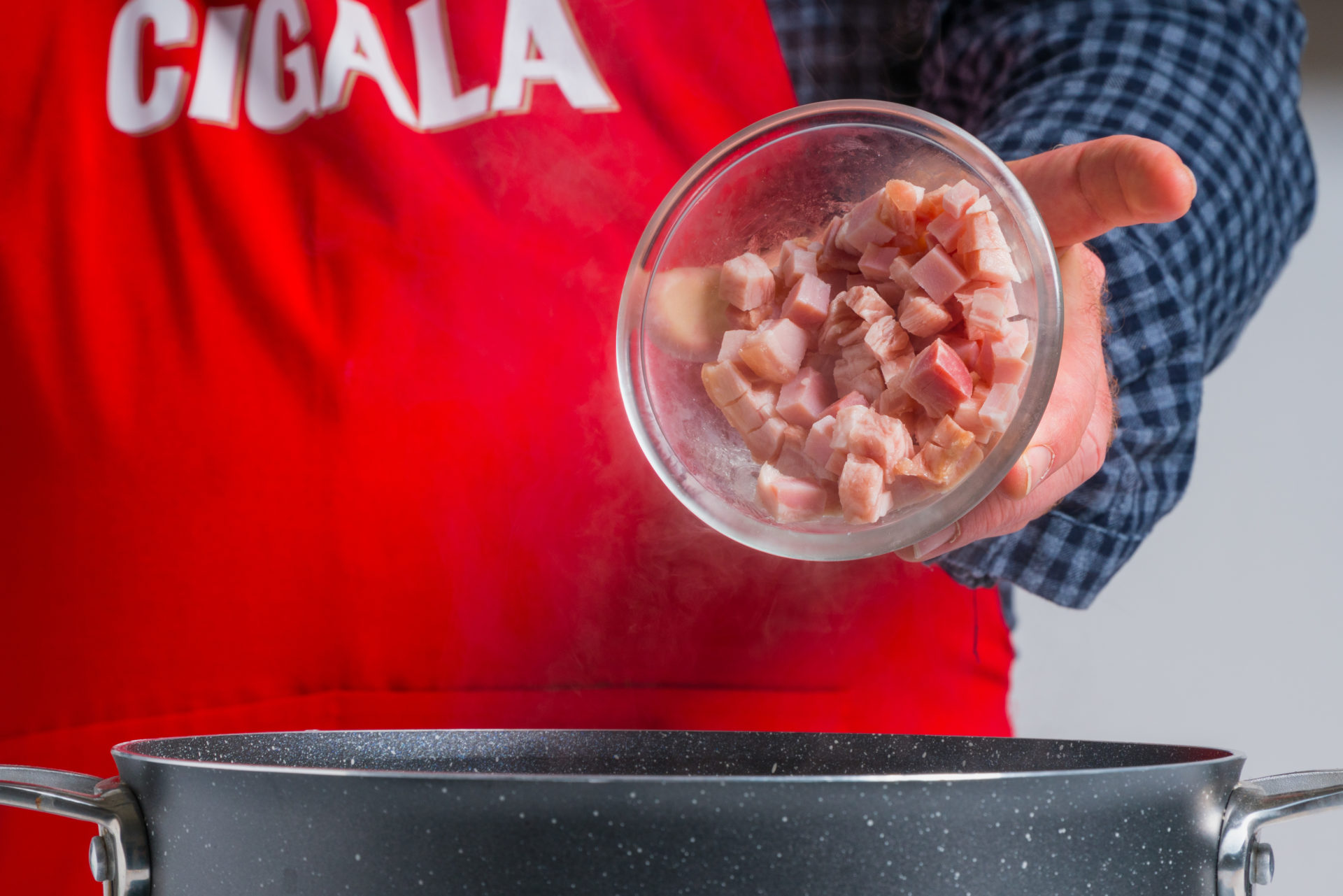 pessoa a adicionar bacon cortado a um tacho