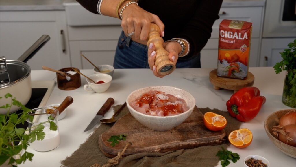 temperar os cubos de frango com sal, pimenta, sumo de laranja, pimentão doce fumado e massa de alho