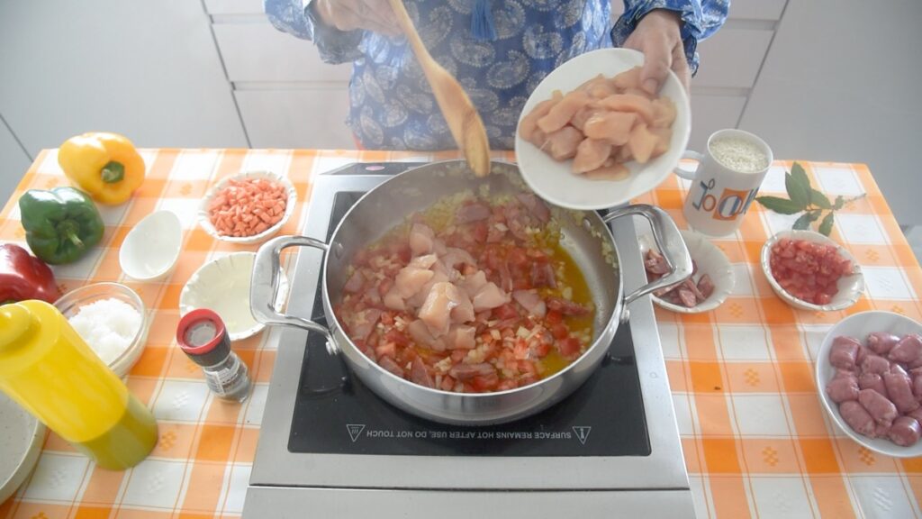 Junte o peito de frango e as salsichas, tempere com sal e pimenta, junte o tomate e o açafrão