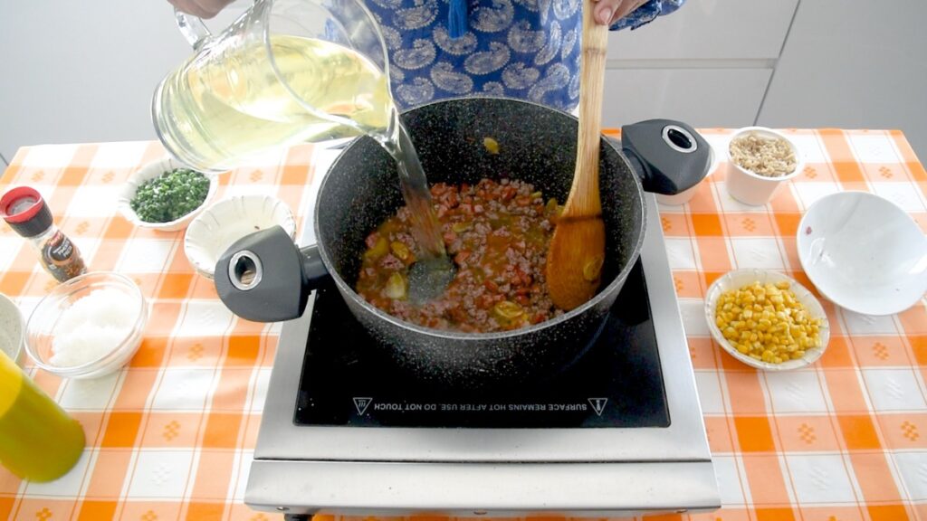 Adicione o caldo de legumes quente, o arroz e o milho cozido.