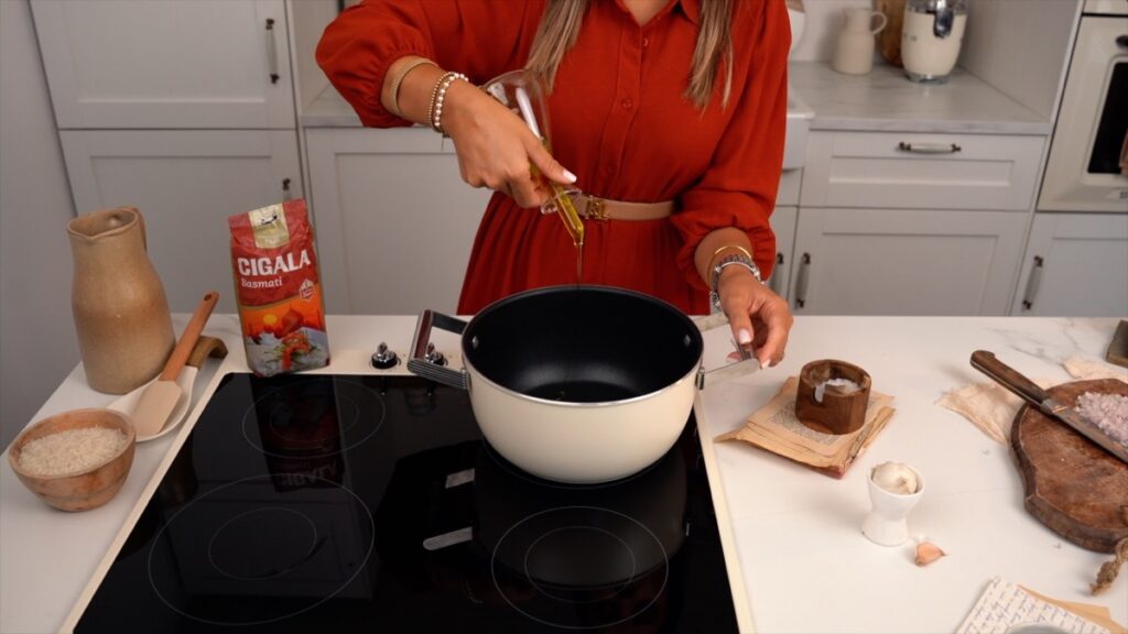 Numa panela, aqueça um fio de azeite e frite levemente o arroz basmati.
