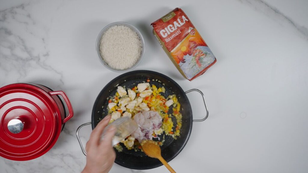 Deixe o frango absorver os sabores e ganhar cor. Tempere com sal e pimenta e adicione as lulas cortadas em pedaços.