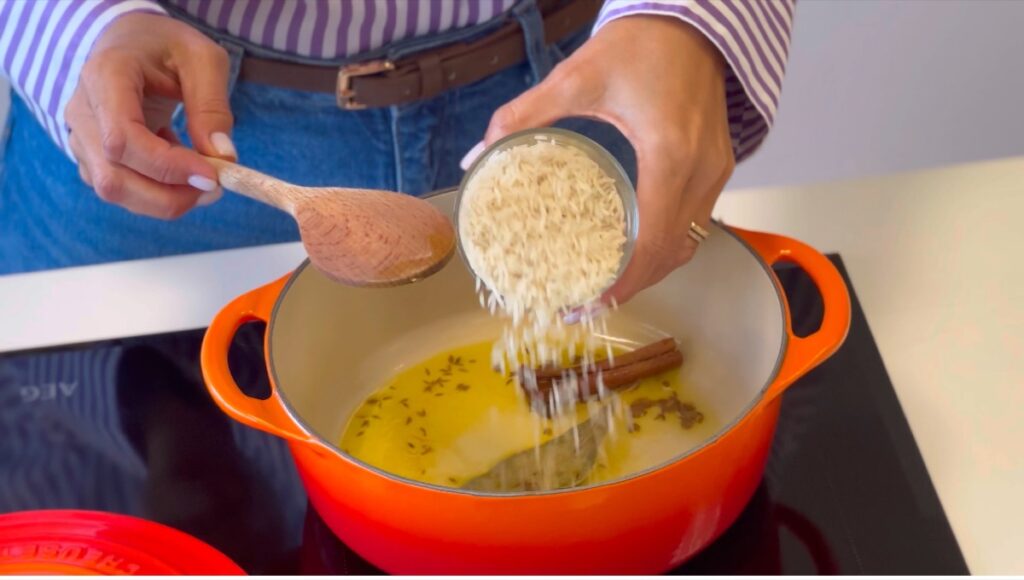 Adicione o arroz basmati ao tacho com as especiarias já ativadas e mexa bem para que todos os grãos fiquem envolvidos nos aromas.